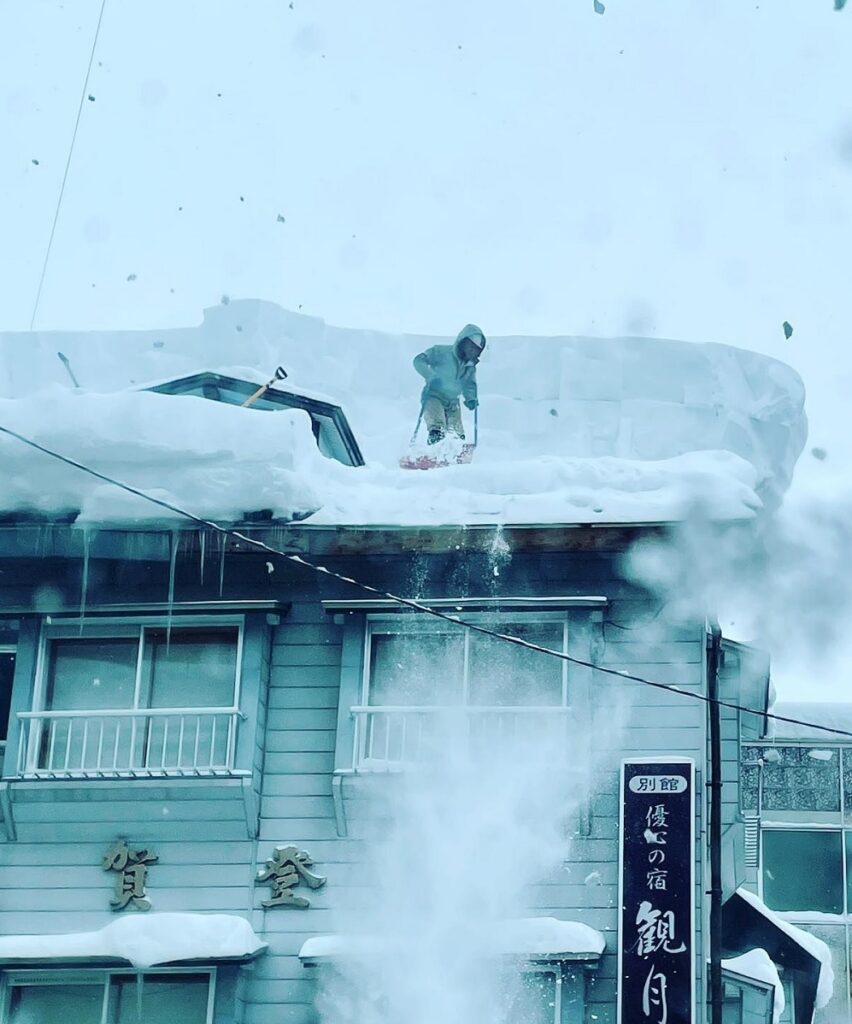 旅館の屋根に登り、雪下ろしをする姿