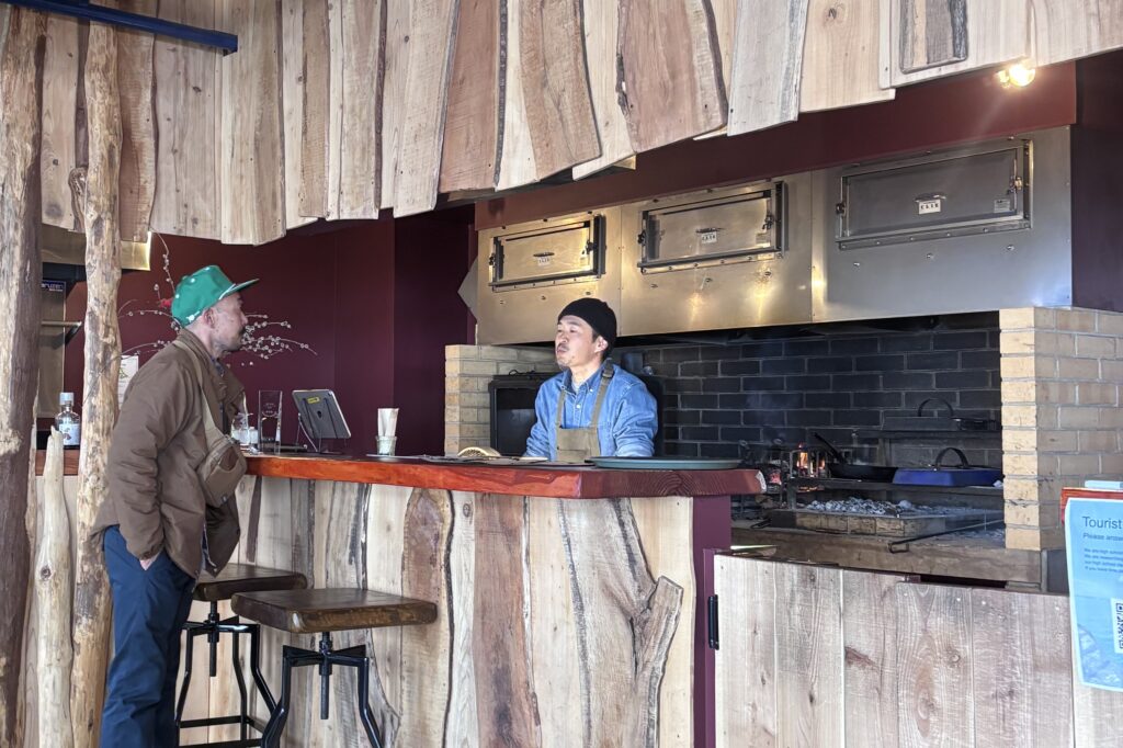 様々な木材を打ち付けた壁、奥は薪ボイラーの熱源を利用した炉だ。